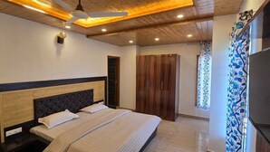A bedroom with a bed, wooden ceiling, wardrobe, and a TV.