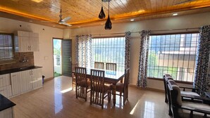 A spacious kitchen with a dining area, wooden ceiling, and large windows.