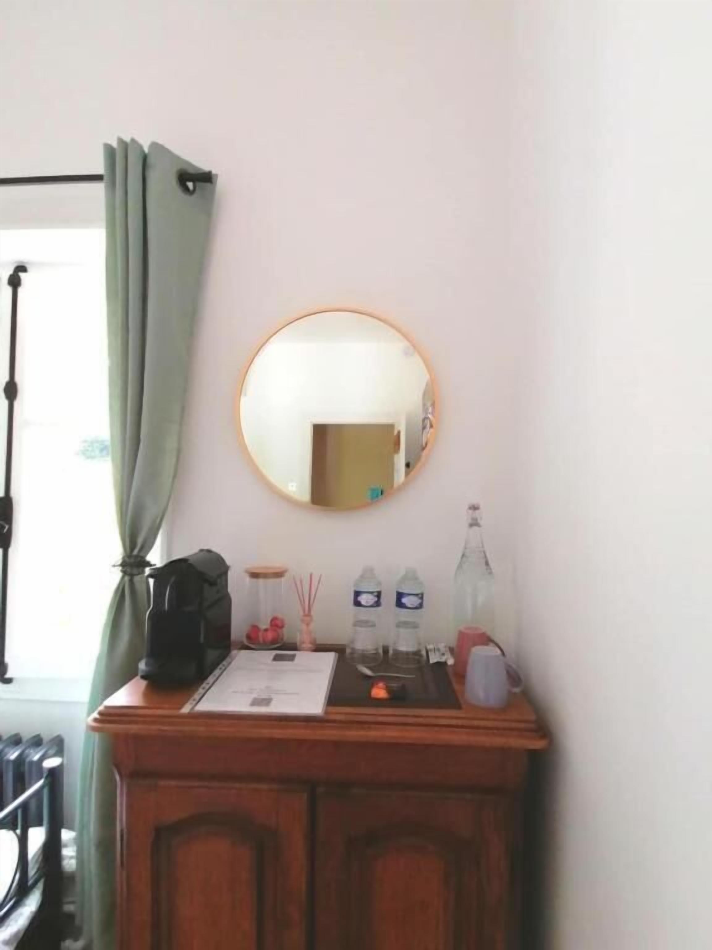 A room with a wooden cabinet, a mirror, a window with curtains, and a door.
