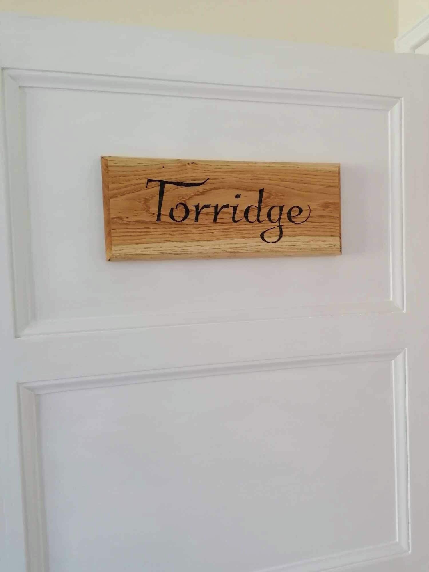 Una puerta blanca con un letrero de madera que dice 'Torridge'.