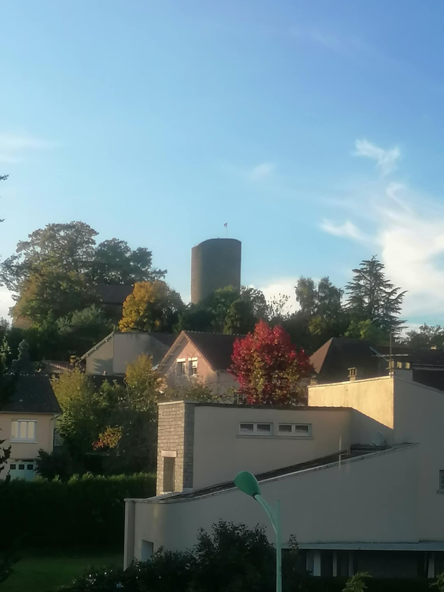 Ett bostadsområde med hus, en cylindrisk byggnad och träd.