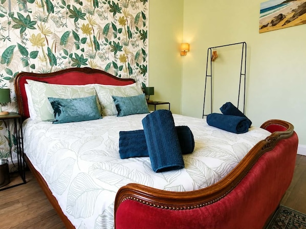 A bed with a red headboard, multiple pillows, and rolled towels. - Trecastle Chambre d'Hotes (Châlus)