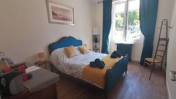 Ein Schlafzimmer mit Bett, Schreibtisch, Stuhl, einem Fenster mit Vorhängen, einer Hängelampe und einer Leiter.