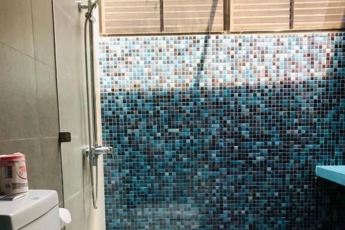 Baño con pared de ducha azulejada, inodoro y lavabo.