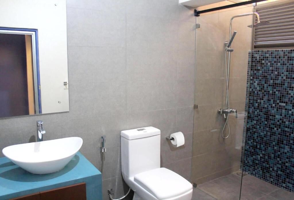Un baño con lavamanos, inodoro y ducha blancos.