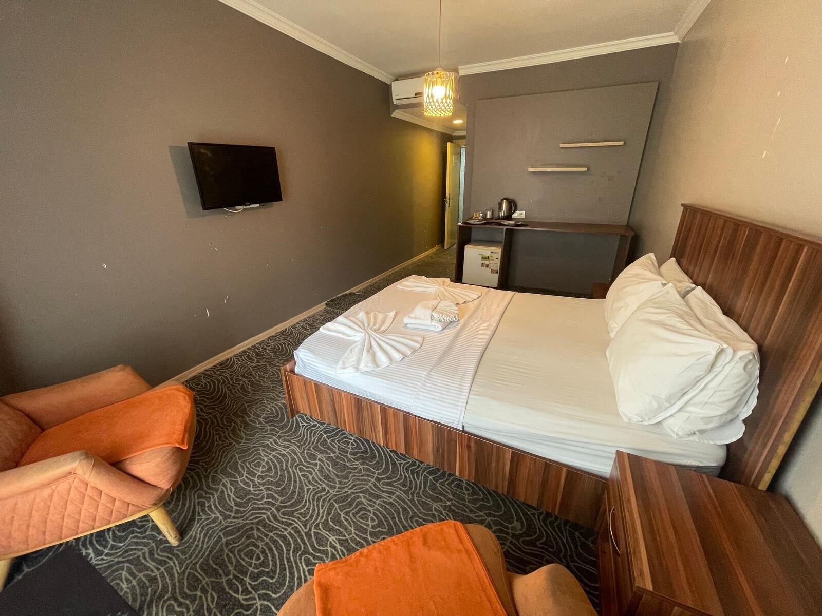 Una habitación de hotel con cama, televisión, escritorio y silla.