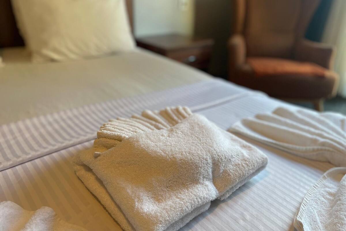 A neatly made bed with a folded towel and a pillow.