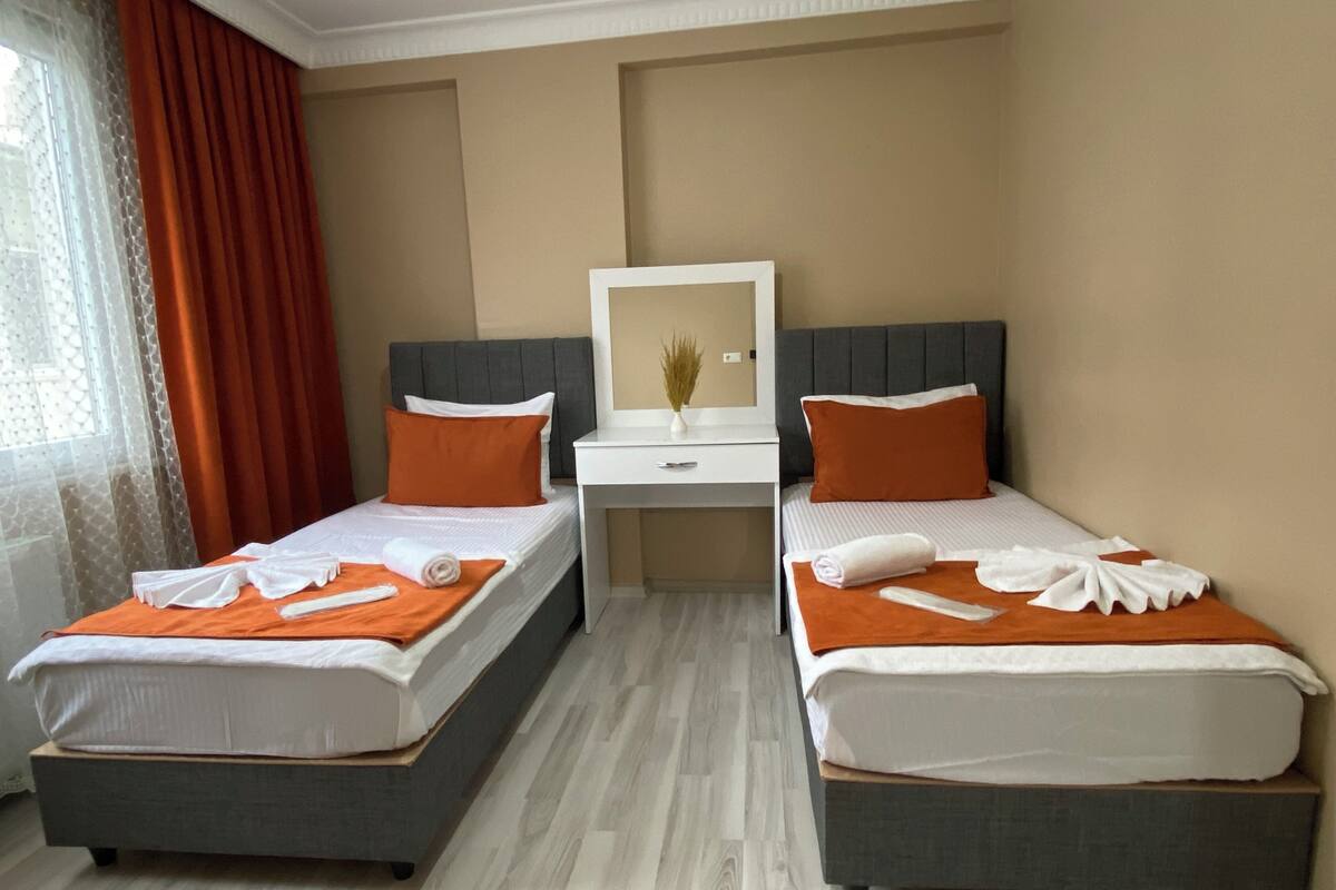 A hotel room with two beds, a desk, and a mirror.
