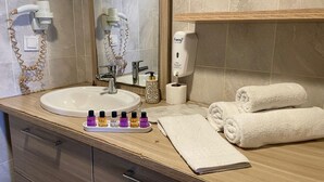 A bathroom with a sink, two hair dryers, a mirror, a soap dispenser, a toilet paper roll, and neatly folded towels. - SER SUITE APART (İstanbul)