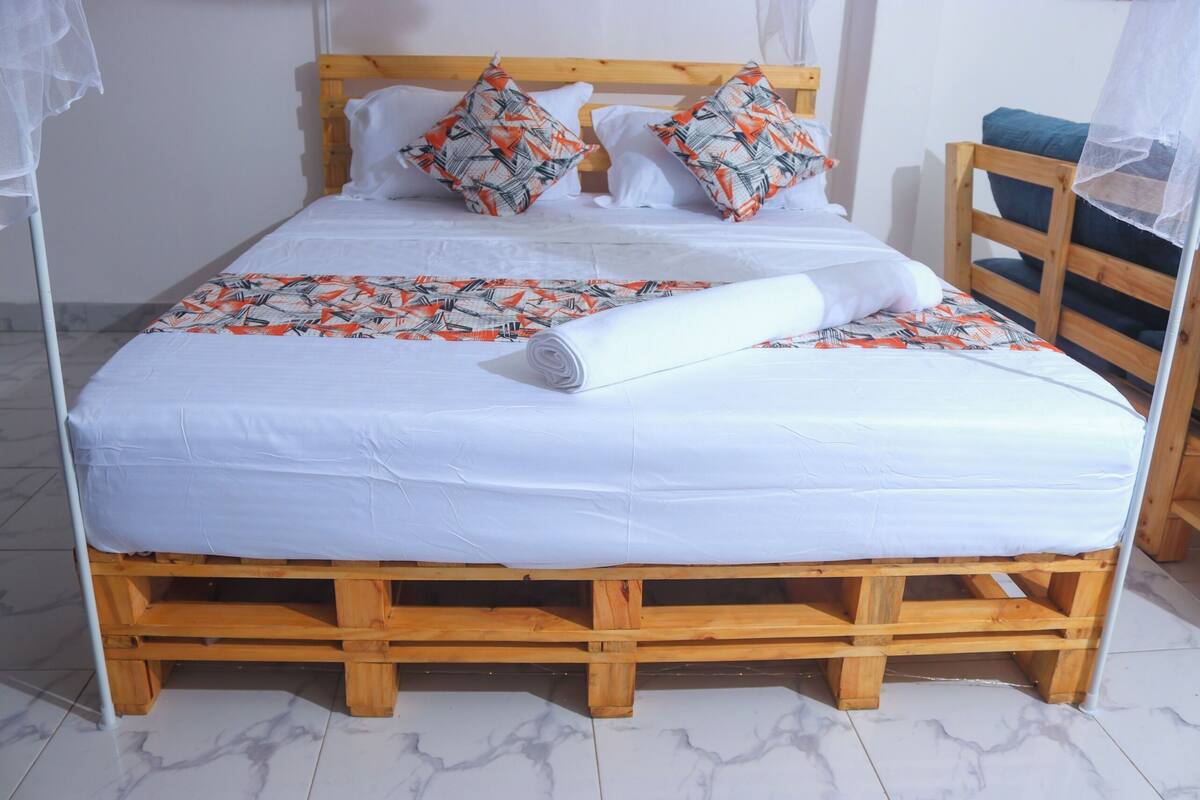 A bed with a wooden frame, white bedding, and patterned pillows.