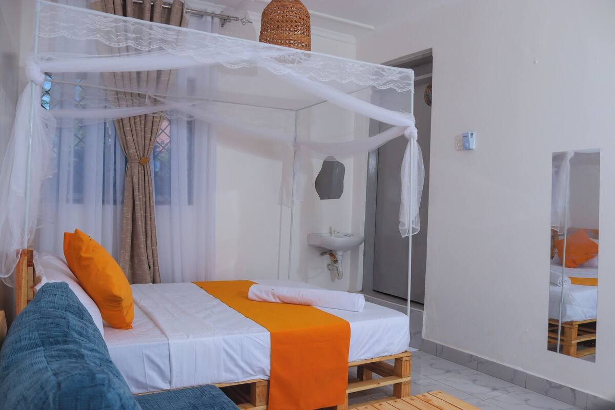 A room with a bed, a small sink, and a window with curtains.