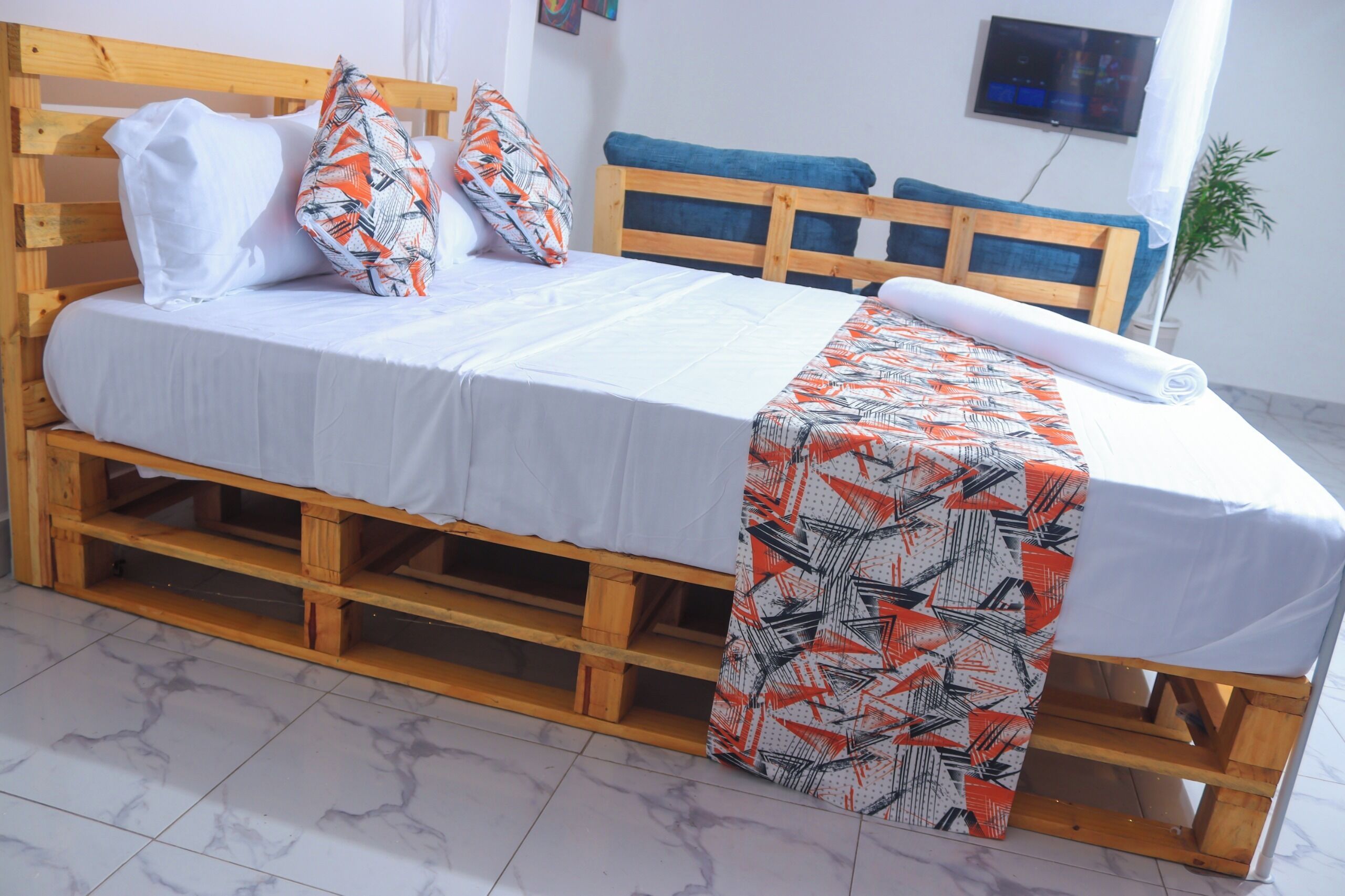 A bed with a white mattress, two pillows, a patterned blanket, and a wooden headboard.