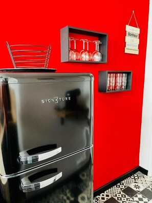 Une cuisine moderne avec un réfrigérateur en acier inoxydable, des murs rouges et un sol à motifs.