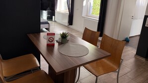 A dining area with a table, chairs, a placemat, a sign indicating a non-smoking room, and a potted plant. - Apartment '3' with Shared Terrace, Balcony and Wi-Fi (Bad Salzuflen)
