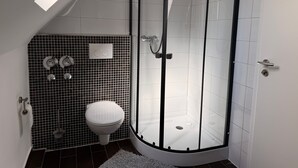 A corner bathroom with a glass-enclosed shower, a toilet, and a tiled backsplash. - Apartment '3' with Shared Terrace, Balcony and Wi-Fi (Bad Salzuflen)
