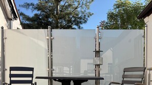 A patio with a table and two chairs, a metal fence, and a building in the background. - Apartment '3' with Shared Terrace, Balcony and Wi-Fi (Bad Salzuflen)