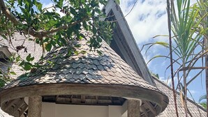 Um edifício em estilo tradicional com telhado de colmo, porta de madeira e entrada com coluna de pedra.