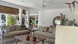 Uma sala de estar ampla com um conjunto de sofás, uma mesa de centro e um ventilador de teto.
