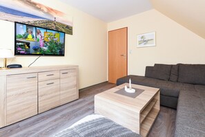 Uma sala de estar com televisão, móveis de madeira, um sofá e uma porta.