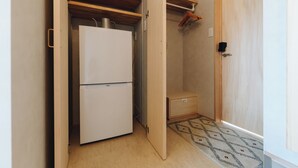 Une pièce de taille modeste, comprenant un réfrigérateur blanc, un meuble en bois et un petit meuble à tiroirs.