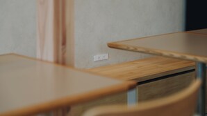 Une table en bois avec un tiroir, une prise de courant murale et une vue partielle d’une chaise.