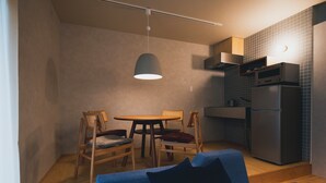 A compact kitchen with a dining area, a sofa, and a hanging light fixture. - cuccou (Aira)