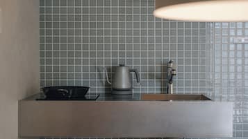 A kitchen with a modern design, featuring a stainless steel sink, a kettle, and a stove.