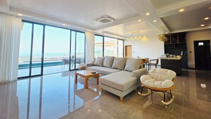 Un amplio salón con un ventanal grande, un sofá, una mesa de centro y un sillón mecedor.