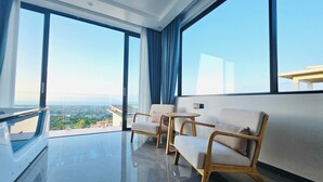 Una habitación moderna con ventanas amplias, un televisor de pantalla plana y dos sillas de madera.