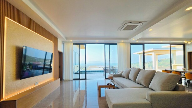 Una sala de estar moderna con un televisor de pantalla plana grande, un sofá, una mesa de centro y un balcón con vistas.