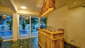 Una zona de recepción con mostrador de madera, puerta de vidrio que da a una piscina y techo con un diseño de madera original.