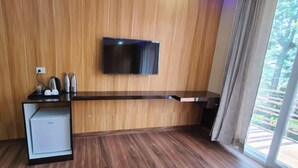 A modern kitchen with a built-in refrigerator, a flat-screen TV mounted on the wall, and a window with curtains. - Indra Stay by Panache Hotels (Baijnath)