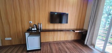 A modern kitchen with a built-in refrigerator, a flat-screen TV mounted on the wall, and a window with curtains.