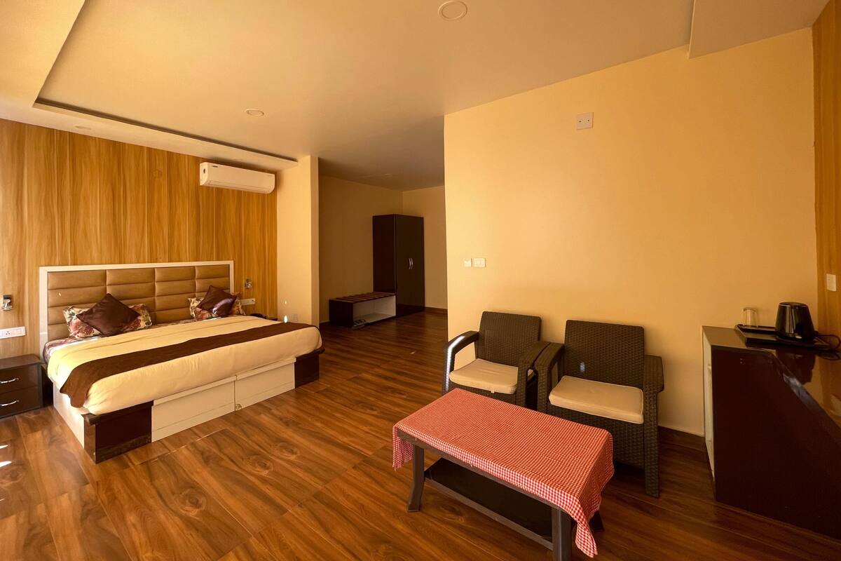 Ein modernes Hotelzimmer mit einem großen Bett, einem Schreibtisch, zwei Stühlen und einem kleinen Tisch.