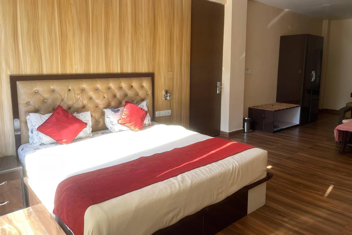 Ein Hotelzimmer mit einem großen Bett, einem Holzkopfende, einem kleinen Tisch und einem Kleiderschrank.