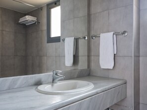 Ein Badezimmer mit einem weißen Waschbecken, einem Spiegel und zwei Handtüchern an Handtuchhaltern.