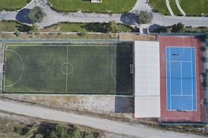 Vista aérea de un complejo deportivo con campo de fútbol y cancha de tenis.