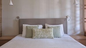 A neatly made bed with a striped bedspread, a headboard, and decorative pillows. - Atlantica Mikri Poli Rhodes (Rhodes)