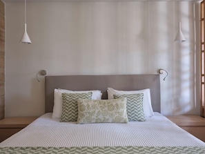 A neatly made bed with a striped bedspread, a headboard, and decorative pillows. - Atlantica Mikri Poli Rhodes (Rhodes)