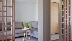 A modern interior with a grey sofa, a small round table, and a large mirror. - Atlantica Mikri Poli Rhodes (Rhodes)