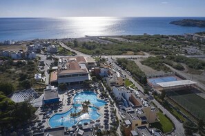 An aerial view of a resort with a central swimming pool, multiple buildings, and a coastline. - Atlantica Mikri Poli Rhodes (Rhodes)