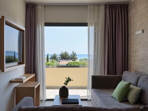 A modern living room with a sofa, a coffee table, a TV, and a view of the sea. - Atlantica Mikri Poli Rhodes (Rhodes)