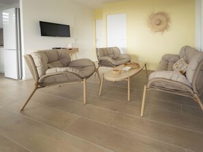 Ein modernes Wohnzimmer mit einer Sofagarnitur, einem Couchtisch und einem flachbildfernseher an der Wand.