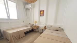 A room with two beds, a small table, a lamp, a wall-mounted air conditioner, and a window. - Villa Ty Kas Soley Sainte Luce, sea view and swimming pool (Sainte-Luce)