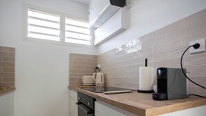A small kitchen with a window, a kettle, a coffee maker, and a toaster. - Villa Ty Kas Soley Sainte Luce, sea view and swimming pool (Sainte-Luce)