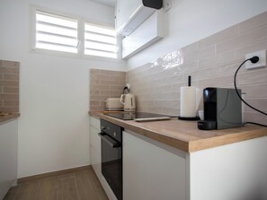 Eine kleine Küche mit Fenster, Wasserkocher, Kaffeemaschine und Toaster.