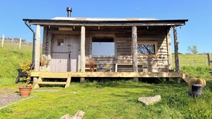 A rustic cabin with a wooden porch, a front door, and a window.