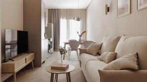 A modern living room with a flat-screen TV, a sofa, a coffee table, and a dining area with chairs and a table. - MH Apartments Blasco Valencia (Valencia)