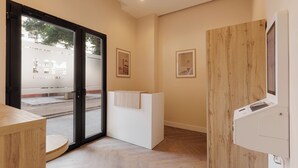 A hotel reception area with a wooden reception desk, a glass door leading outside, and framed pictures on the wall. - MH Apartments Blasco Valencia (Valencia)