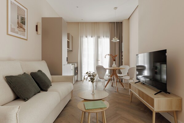 Un salon moderne comprenant un canapé, une table basse, un coin repas et un téléviseur.